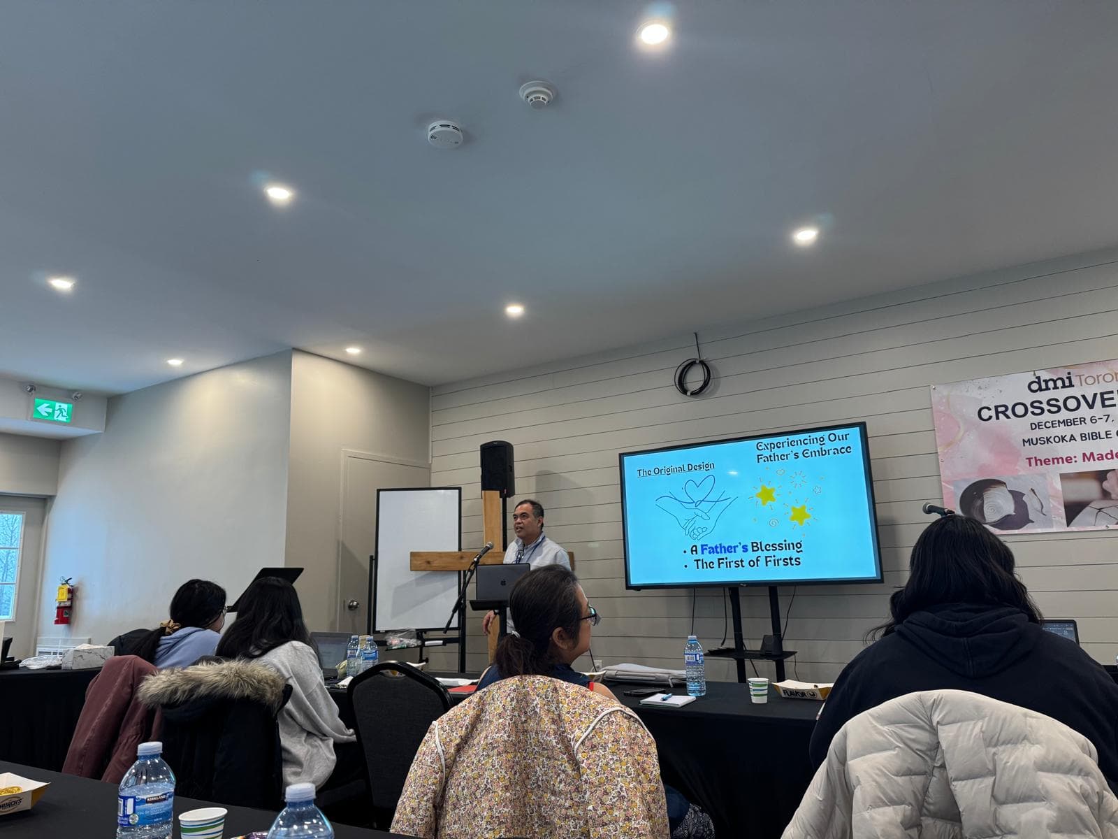 Attendees seated at tables during DMI Toronto's Crossover 2025 retreat as a teacher presents a session.